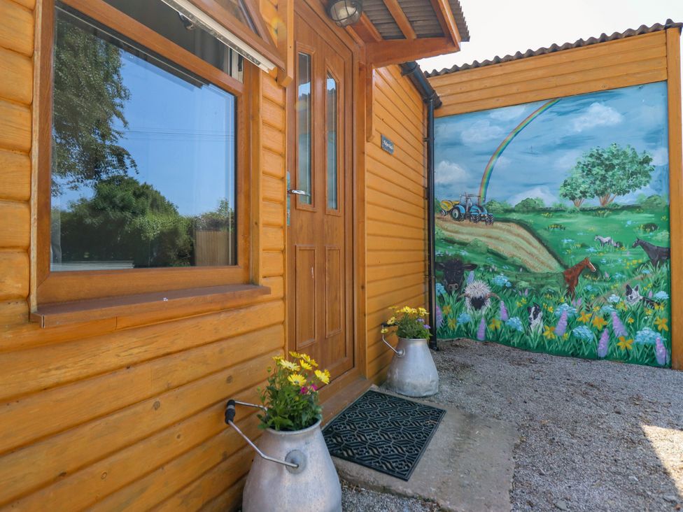 An outdoor area with a wooden door and a mural at Haven Lloc near Holywell