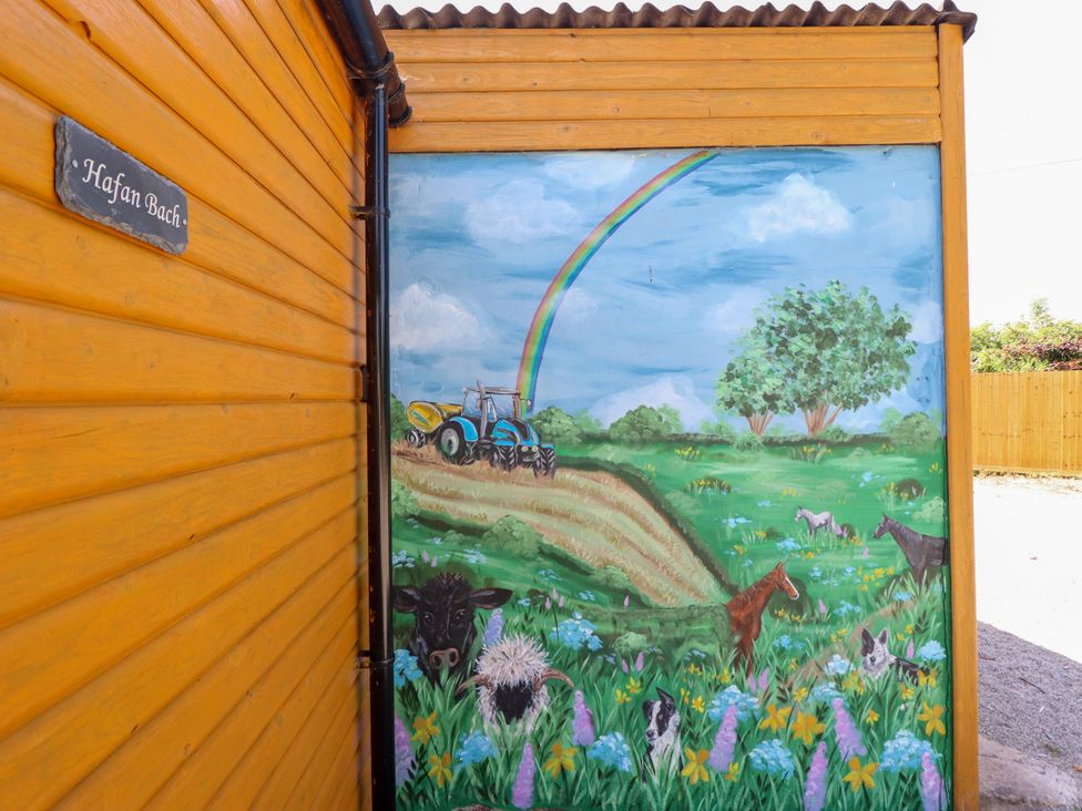 A mural featuring a tractor and animals in a field at Haven Bach near Holywell