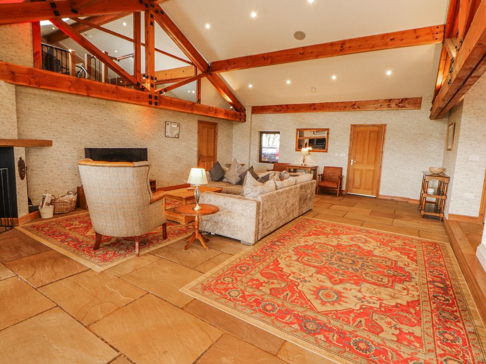 A living room with a sofa, armchair, and a rug at Old Riggs Paddock, Penrith