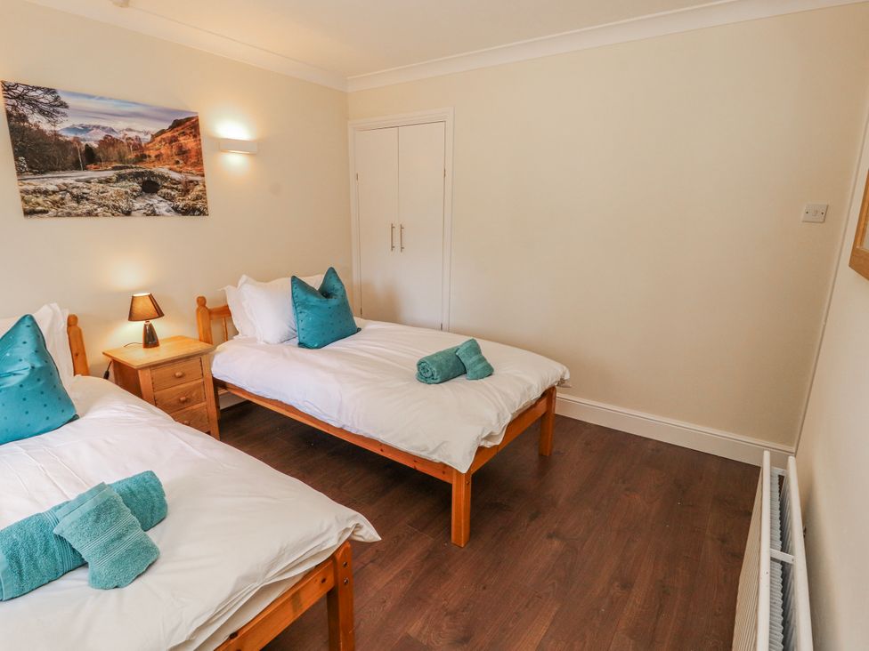 A bedroom with two single beds, a lamp and a wardrobe at Old Riggs Paddock in Penrith