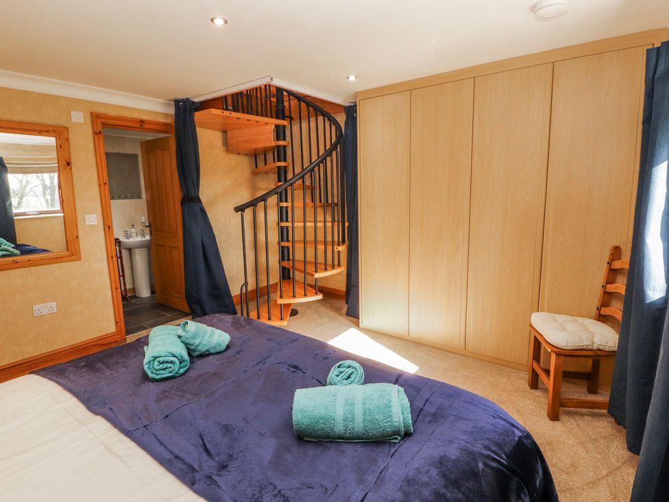 A bedroom with a bed and spiral staircase at Old Riggs Paddock in Penrith