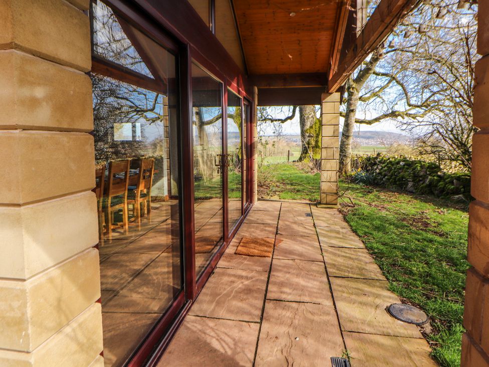 An outdoor area with glass doors and wooden chairs at Old Riggs Paddock Penrith
