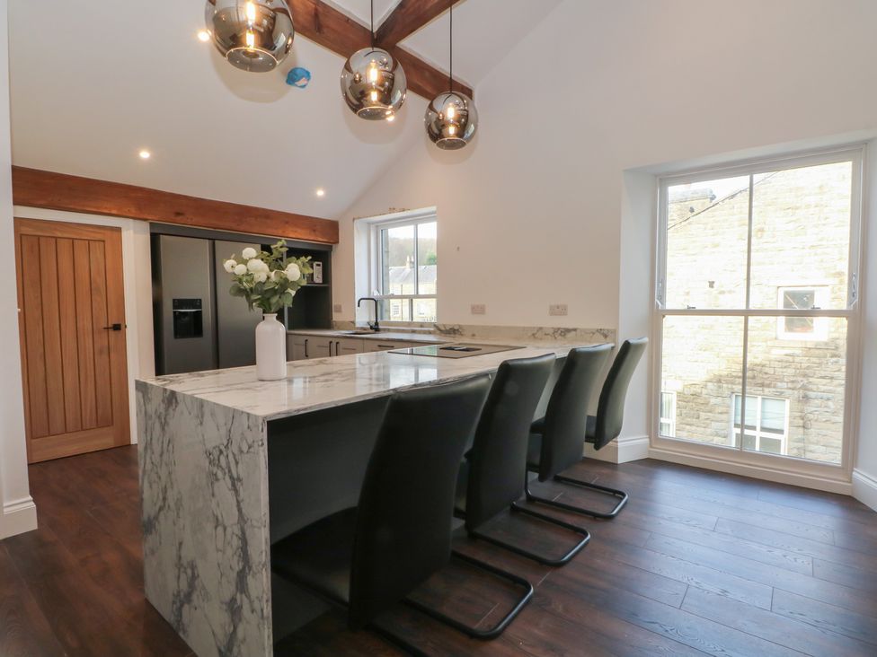 A kitchen with a marble island and stools at The Penthouse at 86 Rossendale