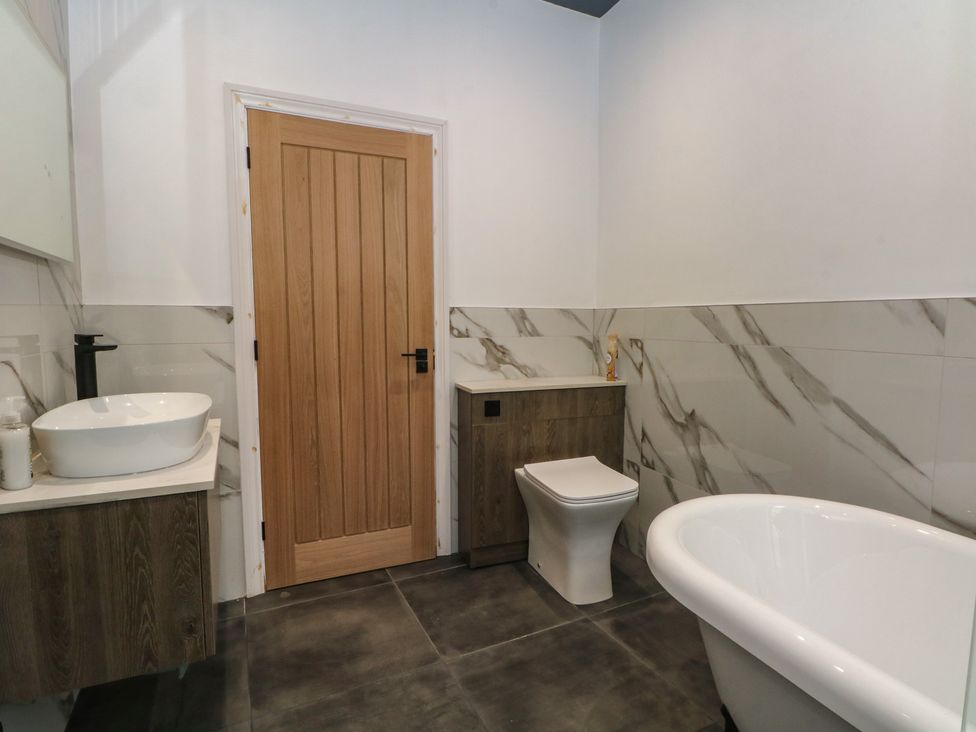 A bathroom with a bathtub, toilet, and washbasin at The Penthouse at 86 in Rossendale