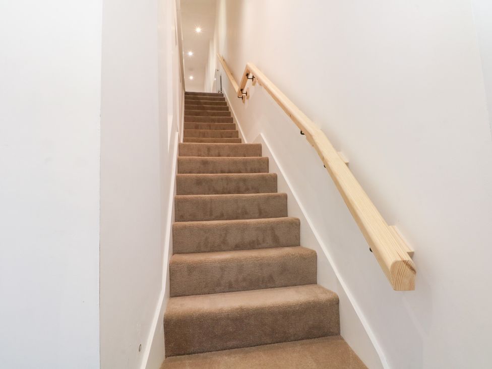 A staircase with carpet and a wooden handrail at The Penthouse at 86 Rossendale