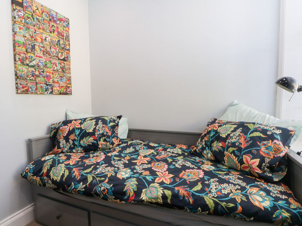 A bed with floral bedding and wall art at The Penthouse at 86 in Rossendale