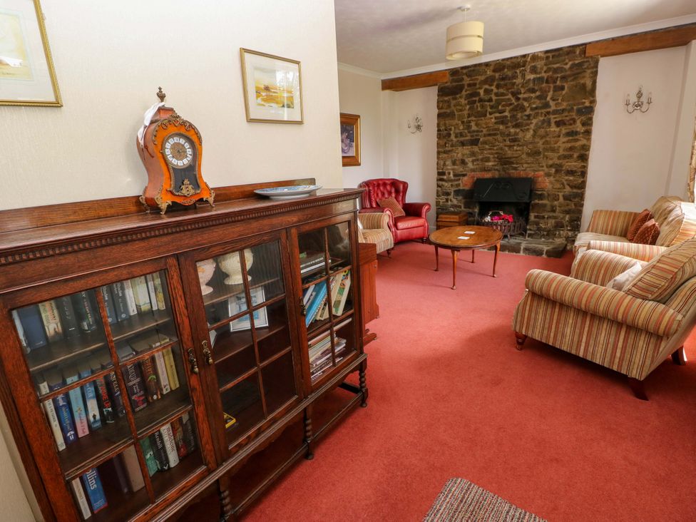 A living room with a bookcase and armchairs at The Sycamores in Llawhaden near Narberth