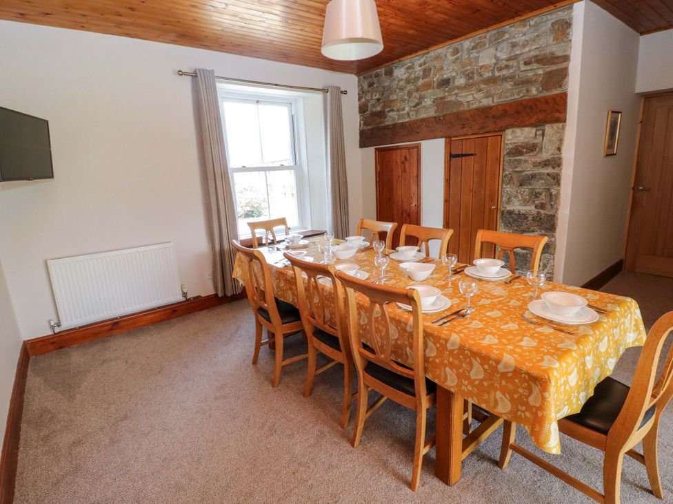 A dining room with a long table set for a meal at The Sycamores in Llawhaden near Narberth