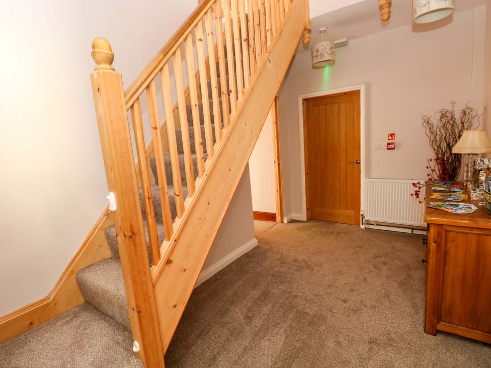 A hallway with a staircase and a table at The Sycamores in Llawhaden near Narberth