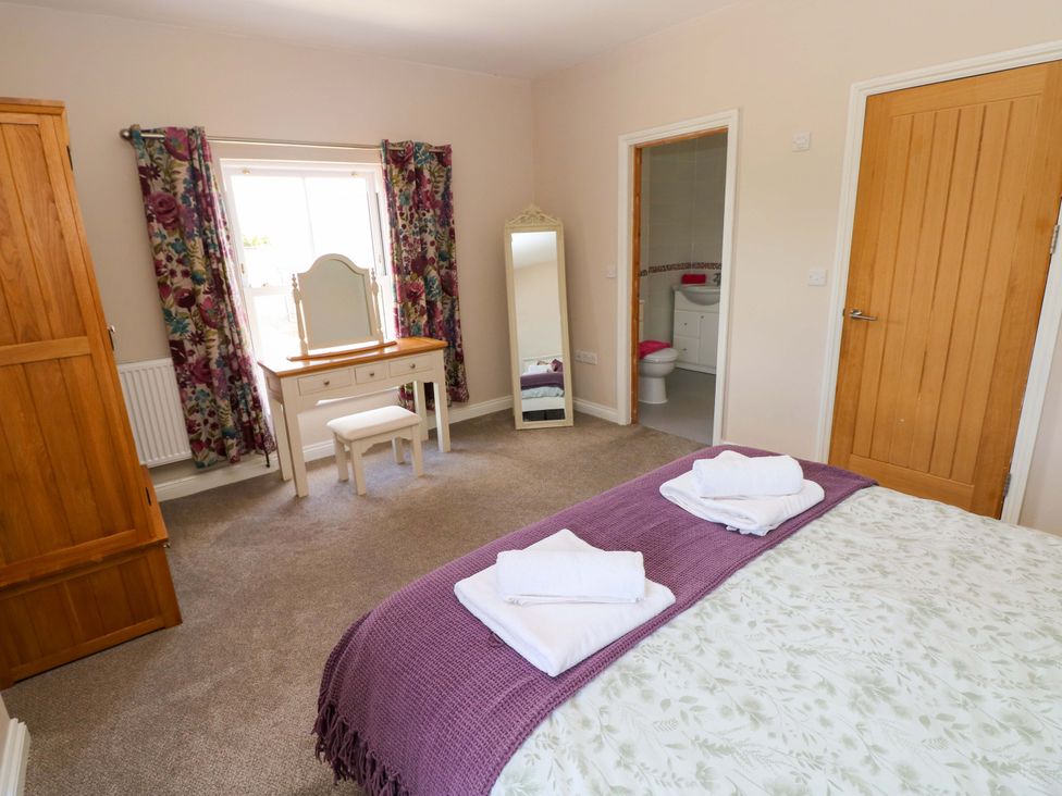 A bedroom with a bed, wardrobe, and vanity table at The Sycamores in Llawhaden near Narberth