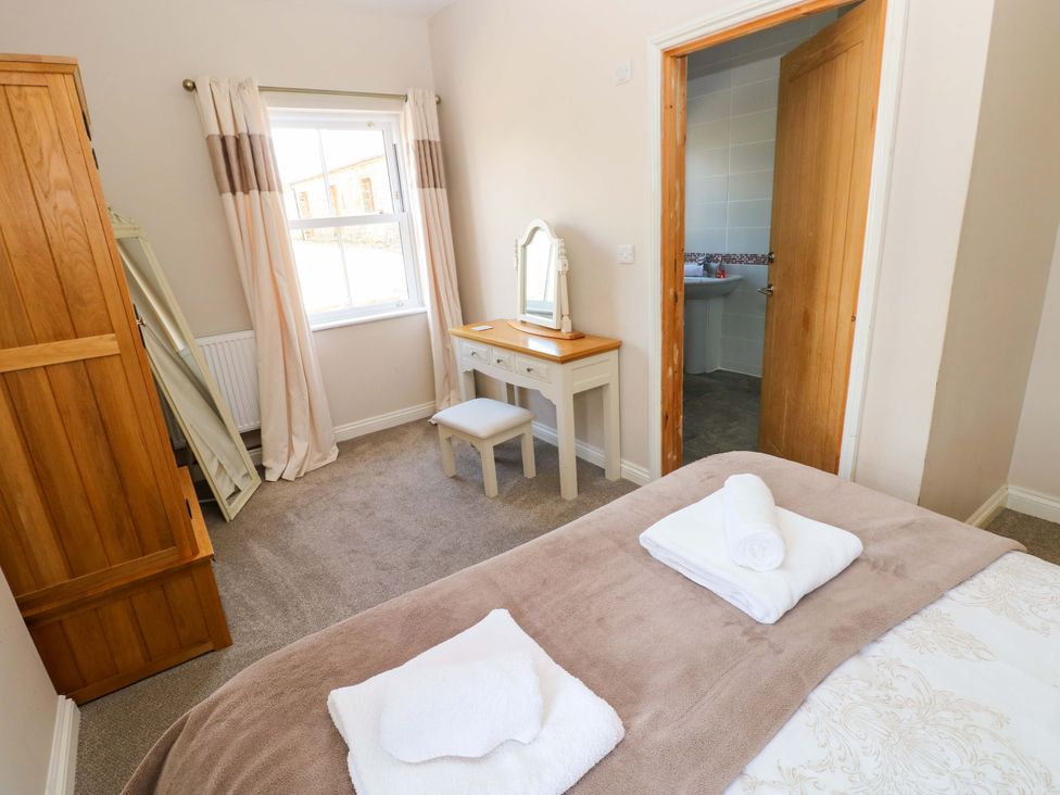 A bedroom with a bed and a dressing table at The Sycamores in Llawhaden near Narberth