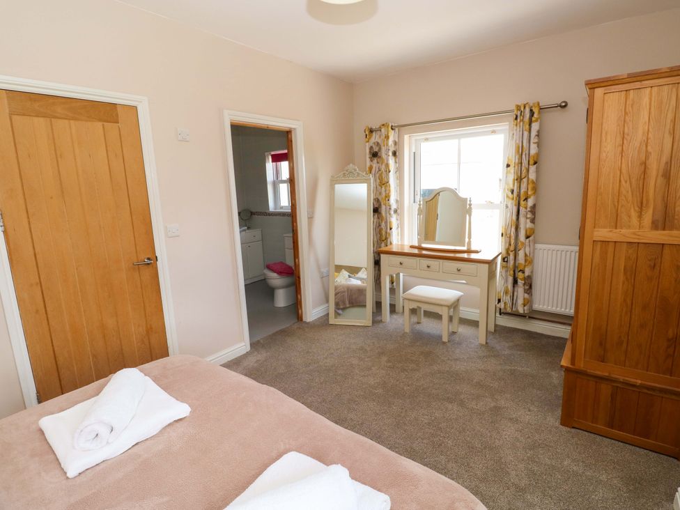 A bedroom with a bed and a dressing table at The Sycamores in Llawhaden near Narberth