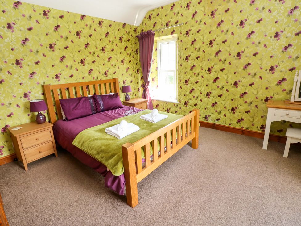A bedroom with a wooden bed and nightstands at The Sycamores in Llawhaden near Narberth