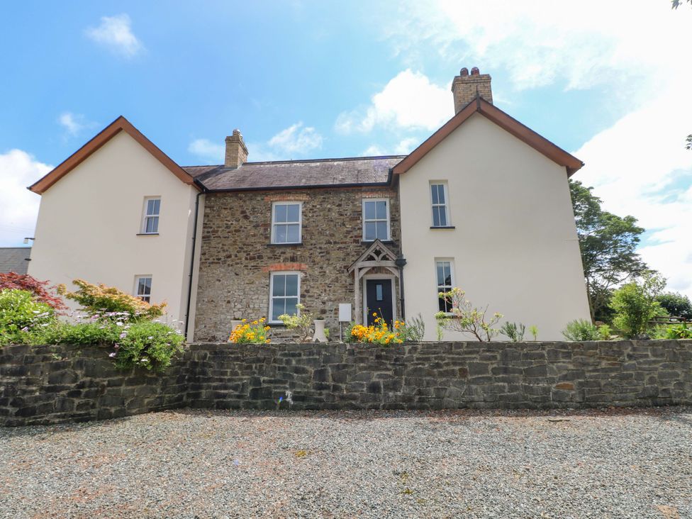 A house with a stone wall and flowers in the front yard at The Sycamores in Llawhaden near Narberth
