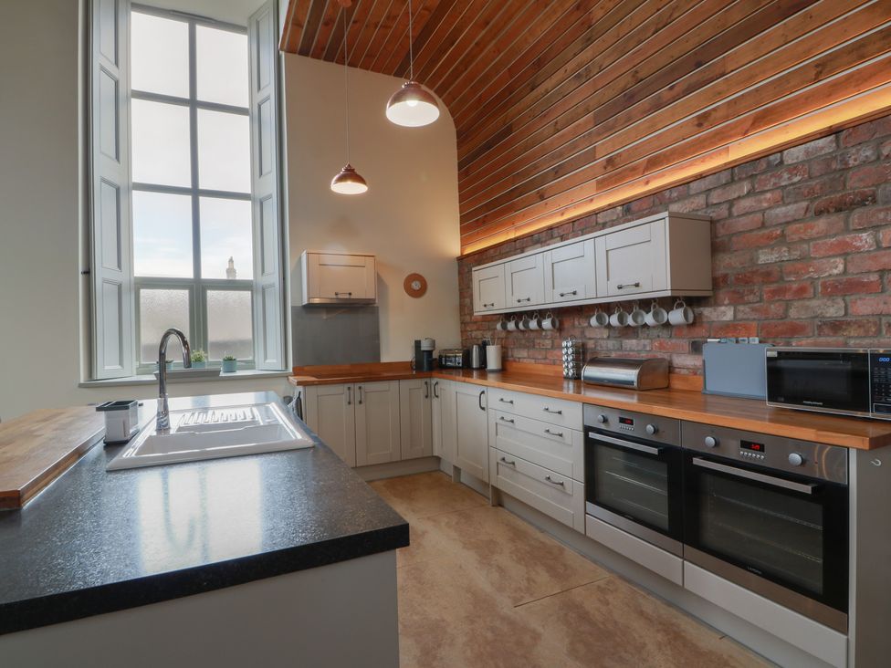 A kitchen with appliances and wooden cabinets at The Old Chapel in Norham
