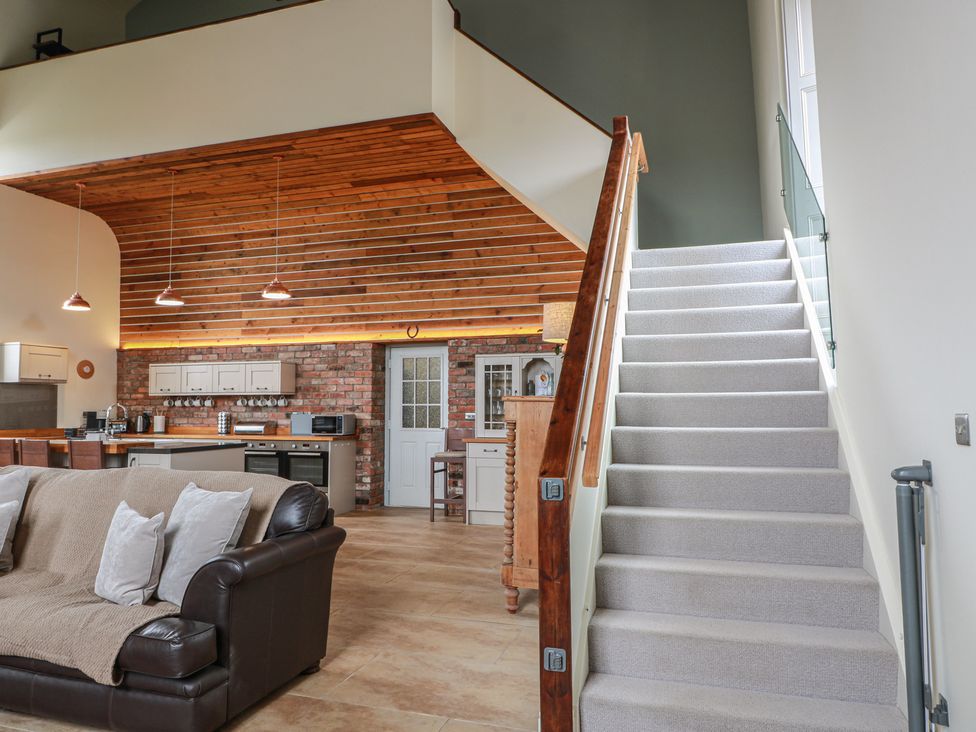 A living room with a staircase and kitchen area at The Old Chapel in Norham