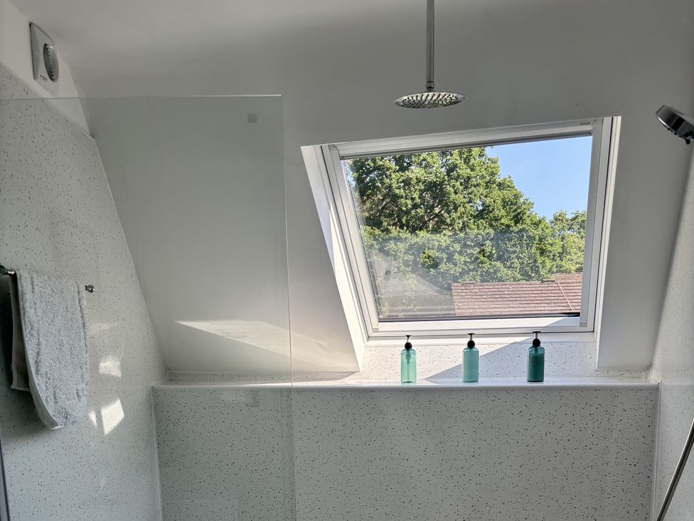 A bathroom with a shower area and window at 8 Church Road Ferndown