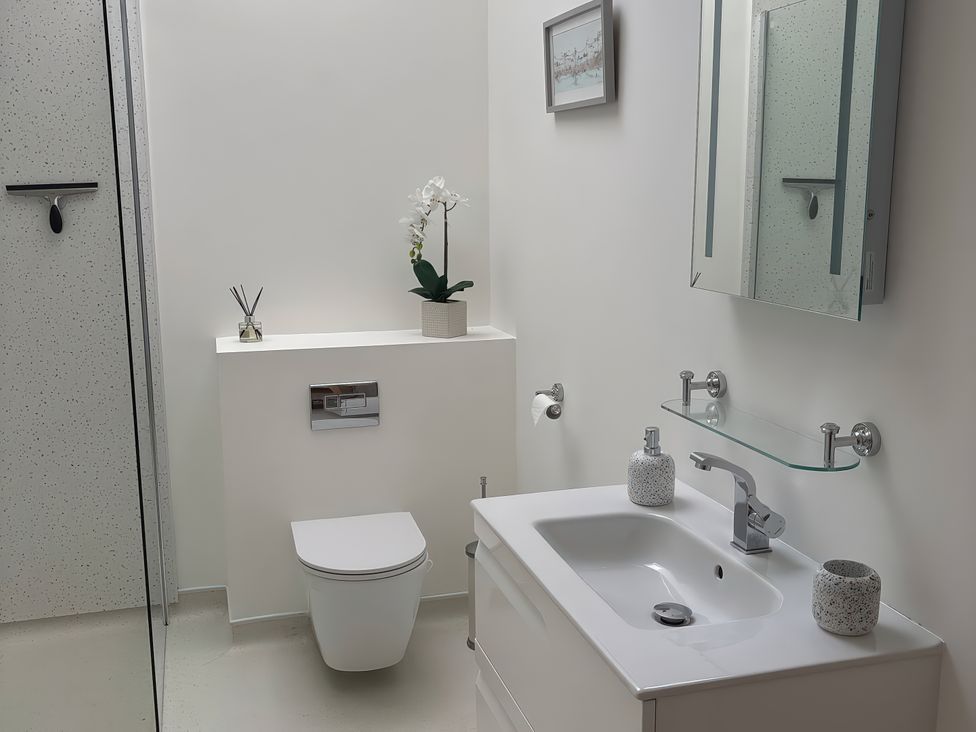 A bathroom with a sink, toilet, and shower at 8 Church Road in Ferndown