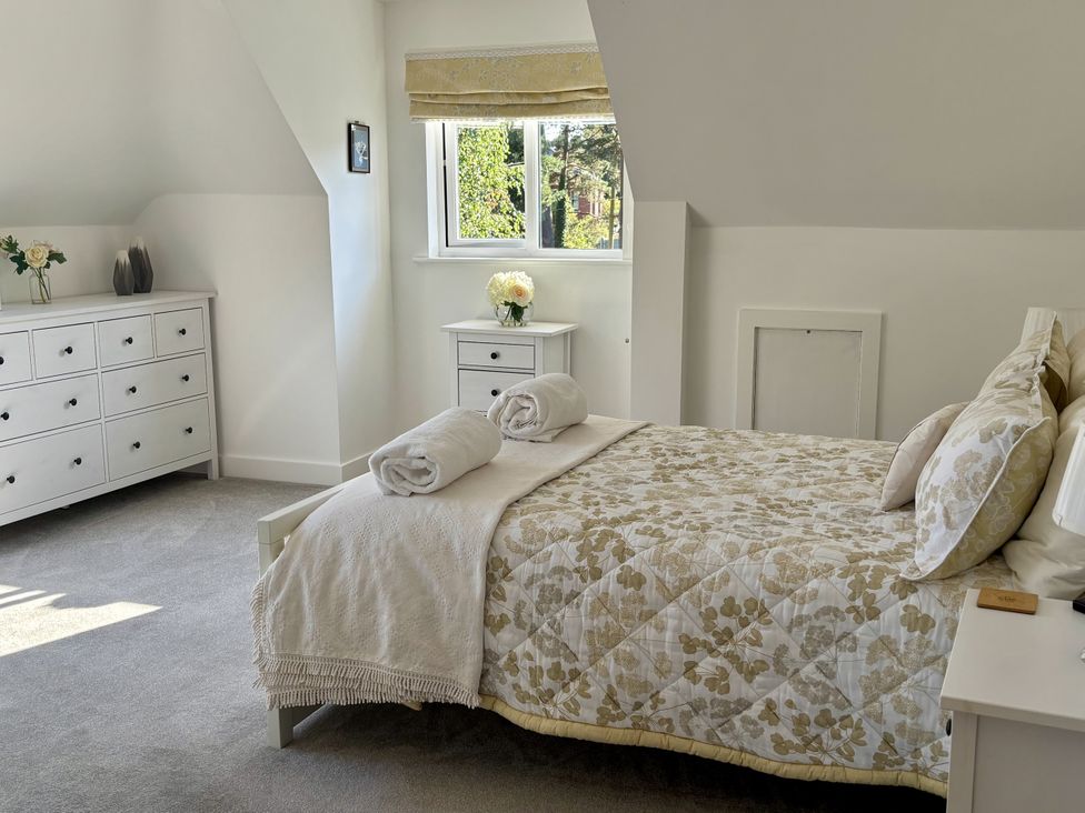 A bedroom with a bed and dresser at 8 Church Road in Ferndown
