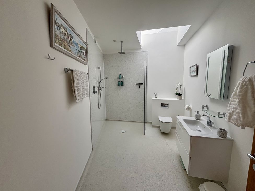 A bathroom with a shower, toilet, and sink at 8 Church Road Ferndown