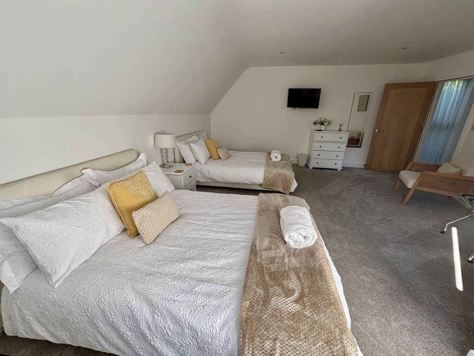 A bedroom with two beds and a TV at 8 Church Road in Ferndown