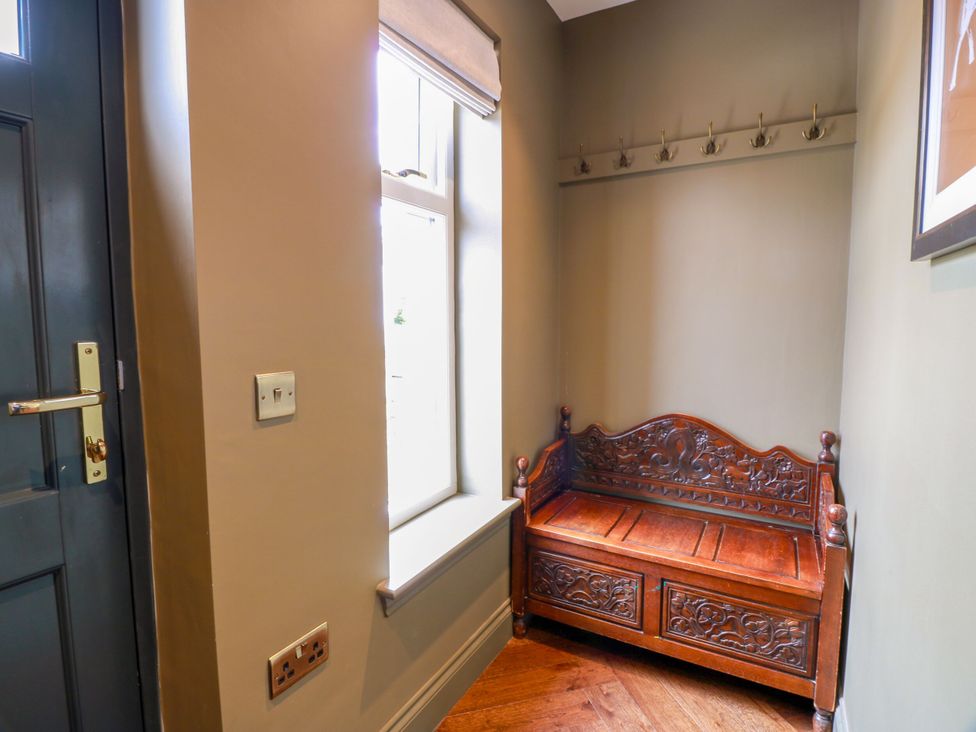 A hallway with a wooden storage bench and coat hooks at Riverwood House in Gatehouse Of Fleet