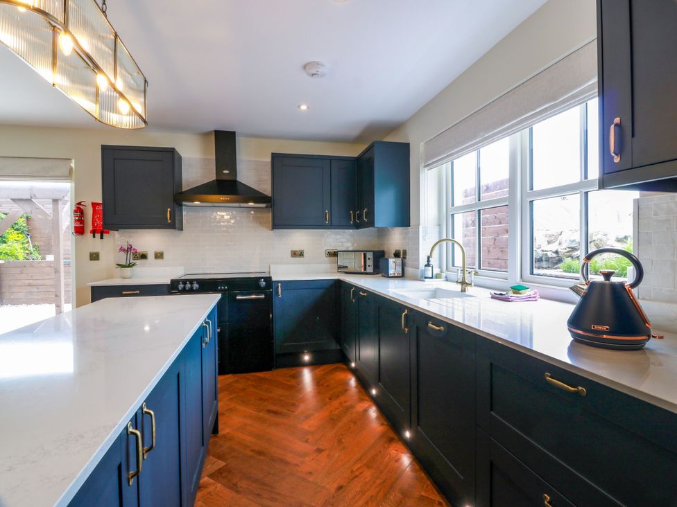 A kitchen with dark cabinets and a sink at Riverwood House in Gatehouse Of Fleet