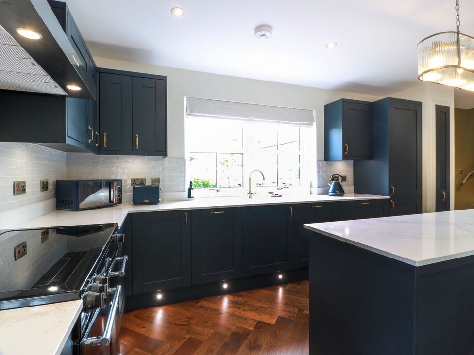 A kitchen with cabinets, sink, microwave, and kettle at Riverwood House Gatehouse Of Fleet