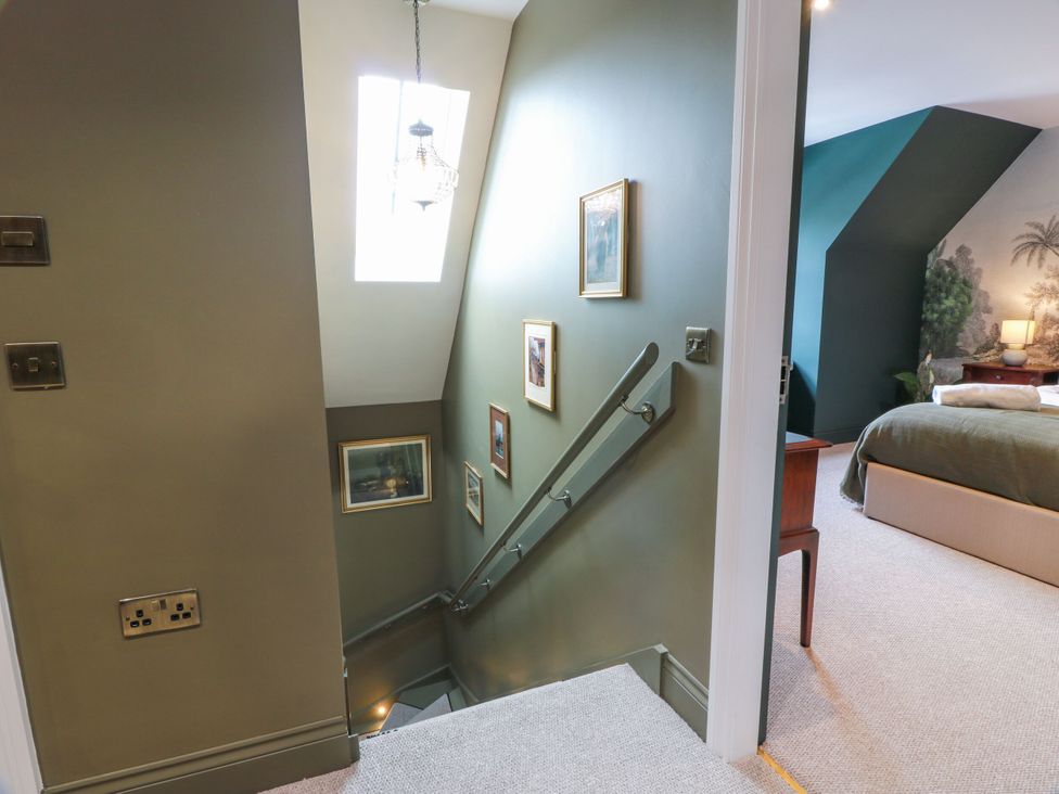 A staircase with pictures on the wall and light fixture at Riverwood House in Gatehouse Of Fleet