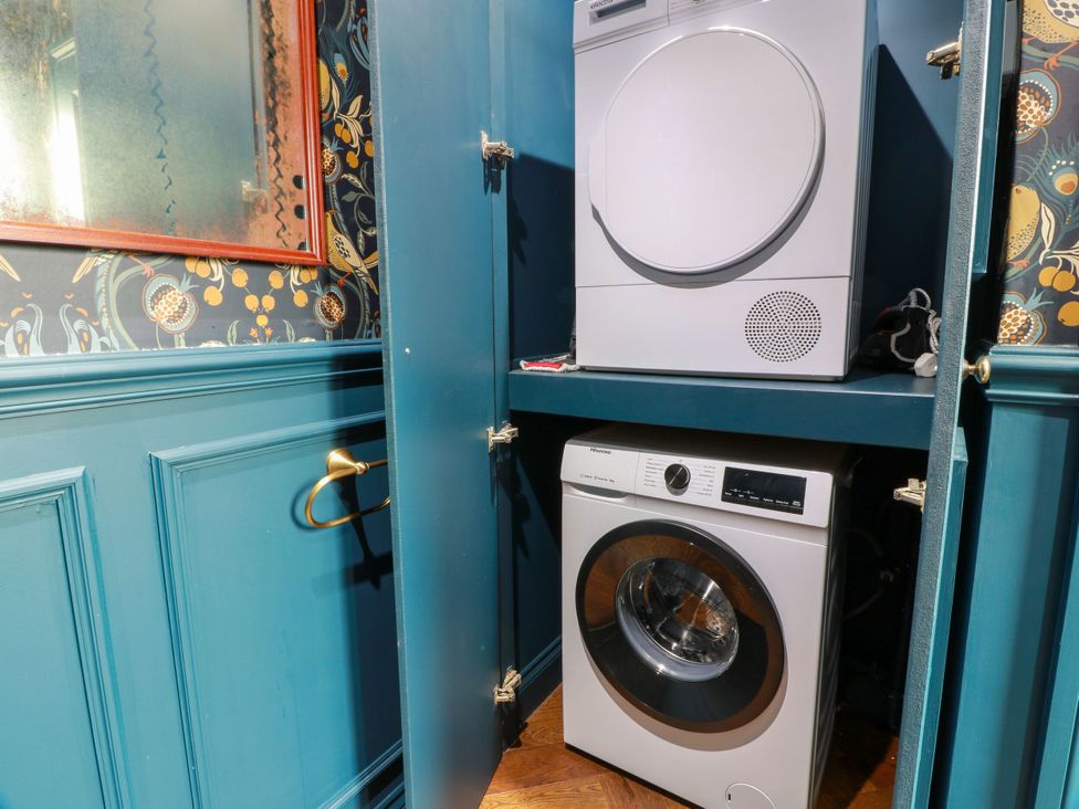 A laundry room with a washer and dryer in a cabinet at Riverwood House in Gatehouse Of Fleet