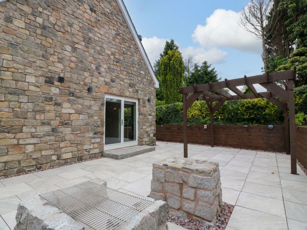 An outdoor patio area with a stone wall and pergola at Riverwood House Gatehouse Of Fleet