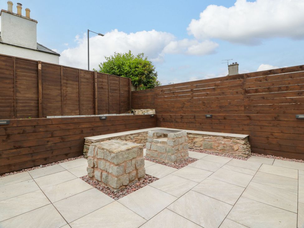A garden with stone seating and wooden fencing at Riverwood House in Gatehouse Of Fleet