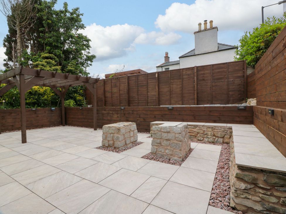 An outdoor seating area with a pergola and stone features at Riverwood House Gatehouse Of Fleet