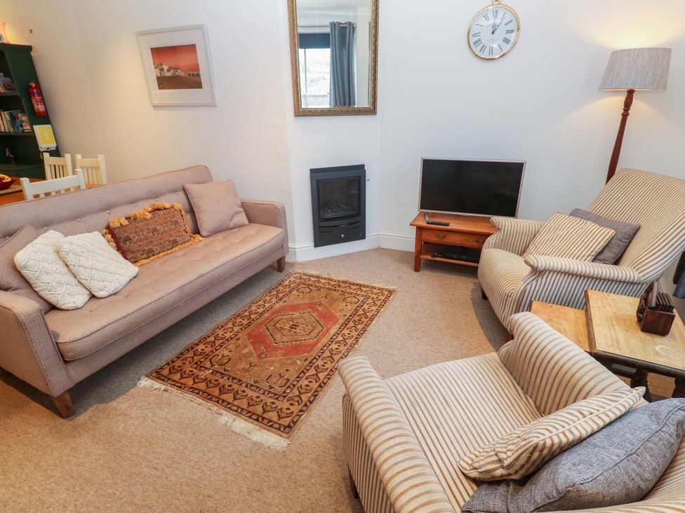 A living room with a sofa, fireplace, and television at Pelican Cottage in St Ives