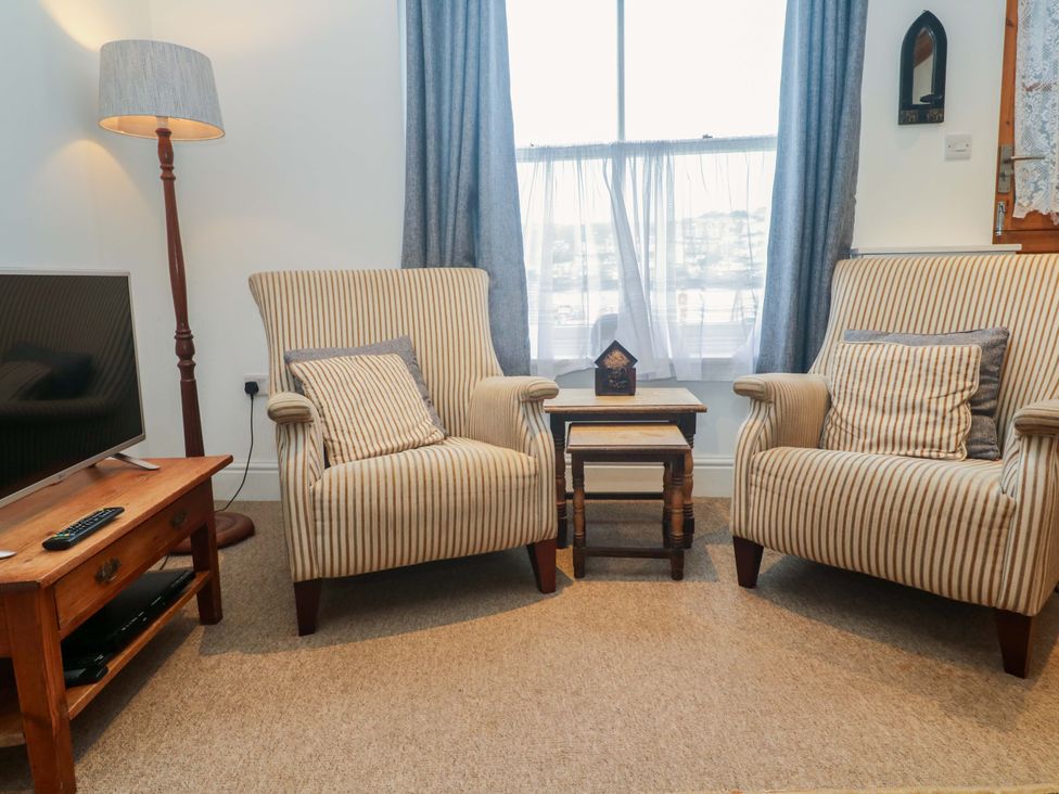 A living room with armchairs and a television at Pelican Cottage in St Ives