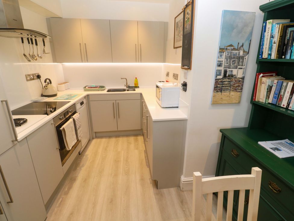 A kitchen with modern appliances and a wooden chair at Pelican Cottage St Ives