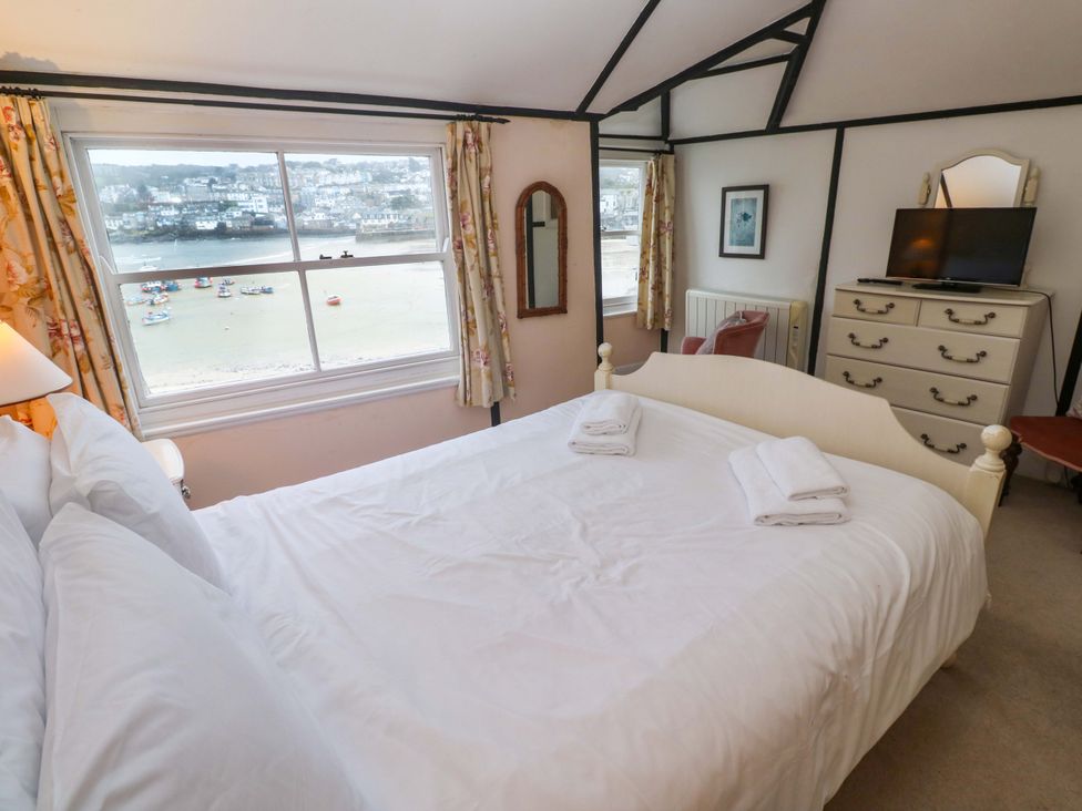 A bedroom with a bed and a television at Pelican Cottage St Ives