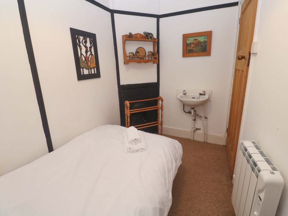 A bedroom with a bed, shelf, and sink at Pelican Cottage St Ives