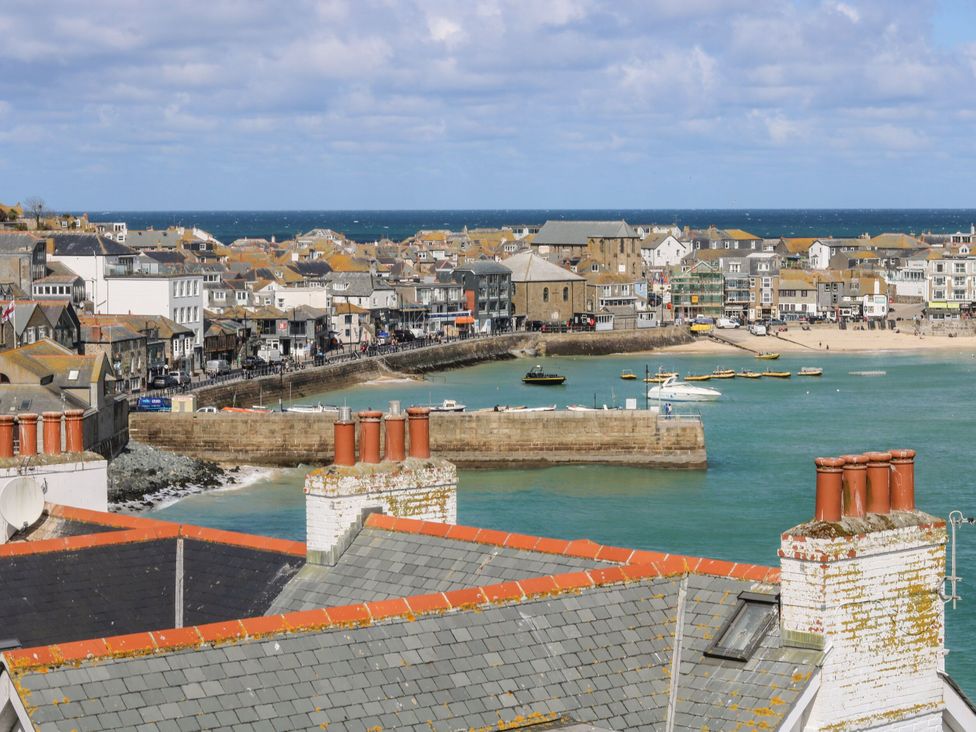 A view of a harbor with boats and town buildings at Pelican Cottage St Ives