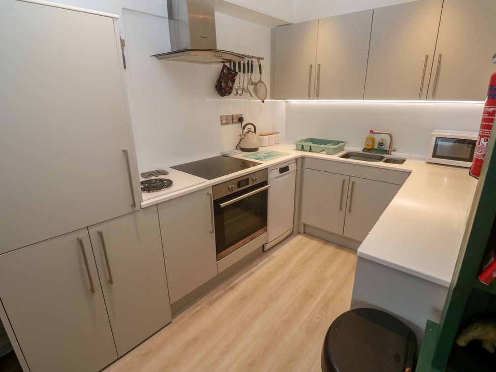 A kitchen with modern appliances and storage at Pelican Cottage in St Ives