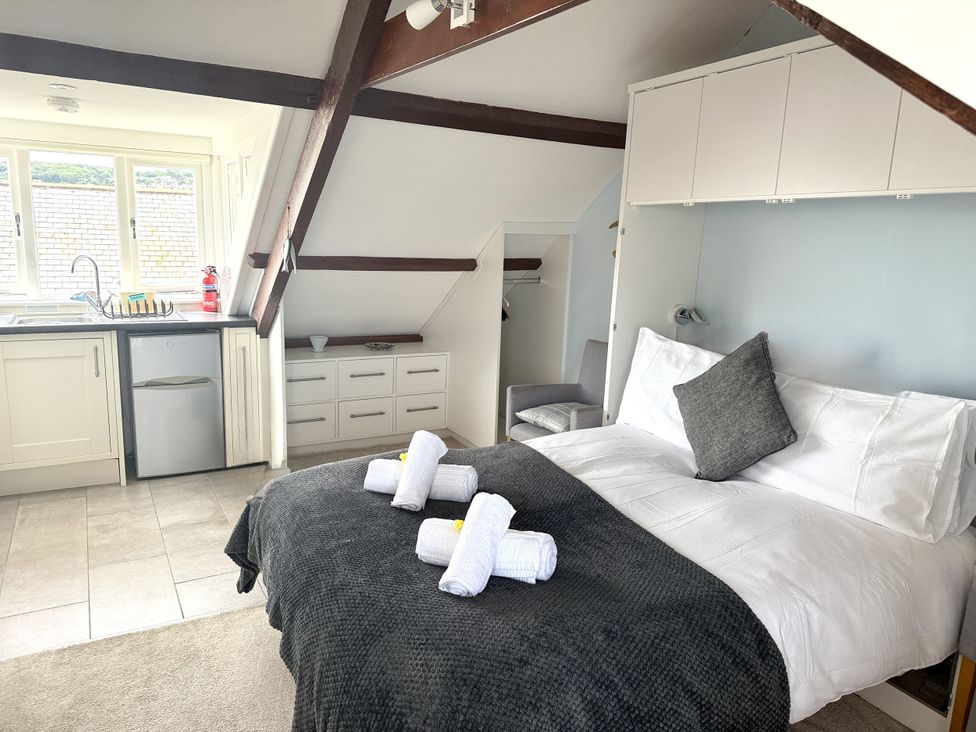 A bedroom with a bed and kitchenette at Crows Nest in St Ives