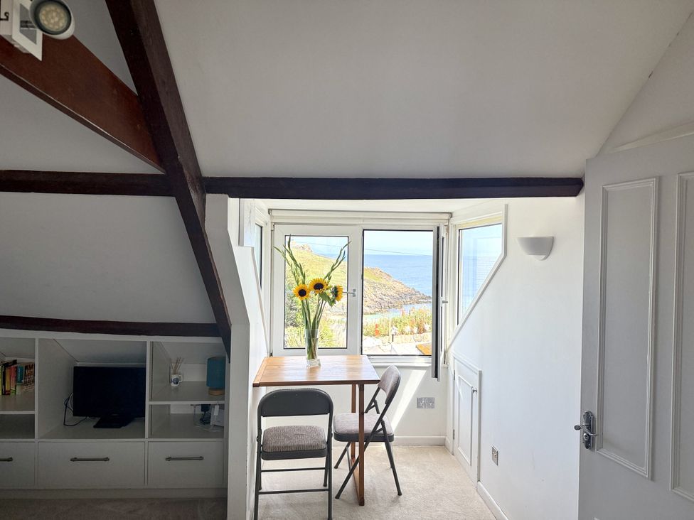 A room with a table and chair overlooking the sea at Crows Nest in St Ives