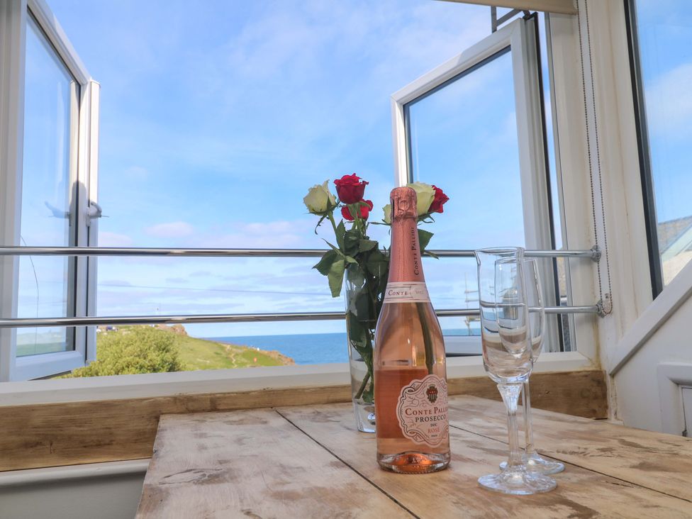 A table with wine glasses and a bottle near a window at Seagulls Nest in St Ives