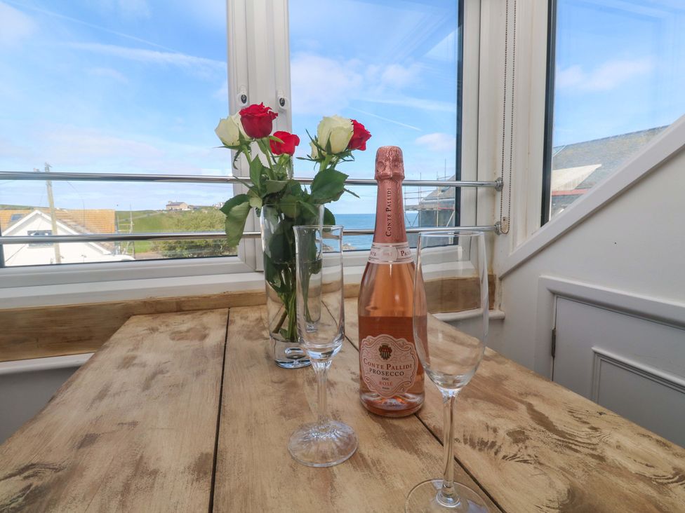 A dining area with a bottle of prosecco and glasses at Seagulls Nest in St Ives