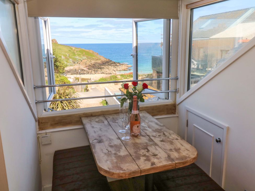 A dining room with a table, glasses, and a bottle at Seagulls Nest in St Ives