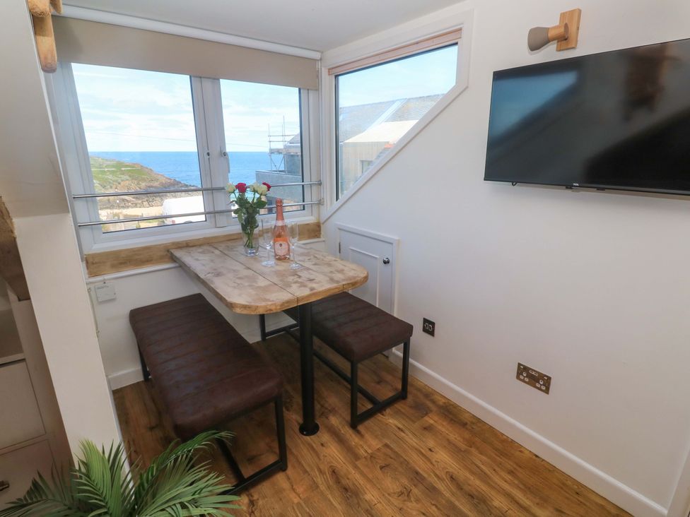 A dining room with a table and benches at Seagulls Nest in St Ives