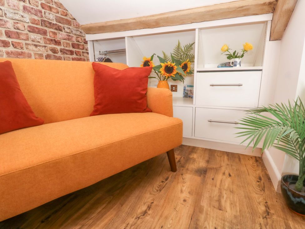 A snug with an orange sofa and flowers at Seagulls Nest St Ives