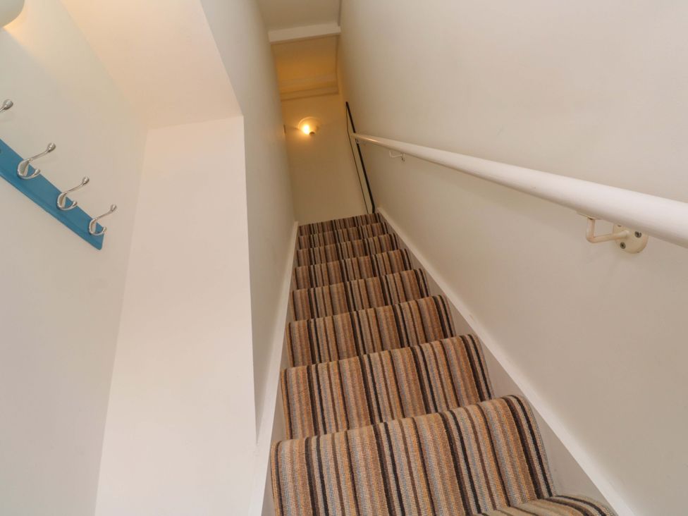 A staircase with striped carpet and a handrail at Seagulls Nest in St Ives