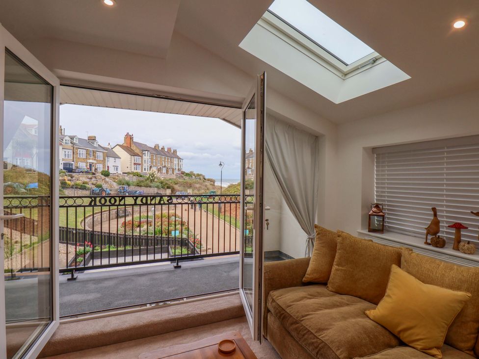 A living room with a balcony door and a sofa at Sandy Nook in Redcar
