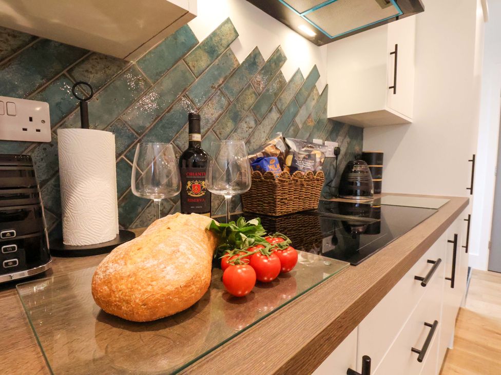 A kitchen countertop with bread, tomatoes, wine and glasses at Sandy Nook in Redcar